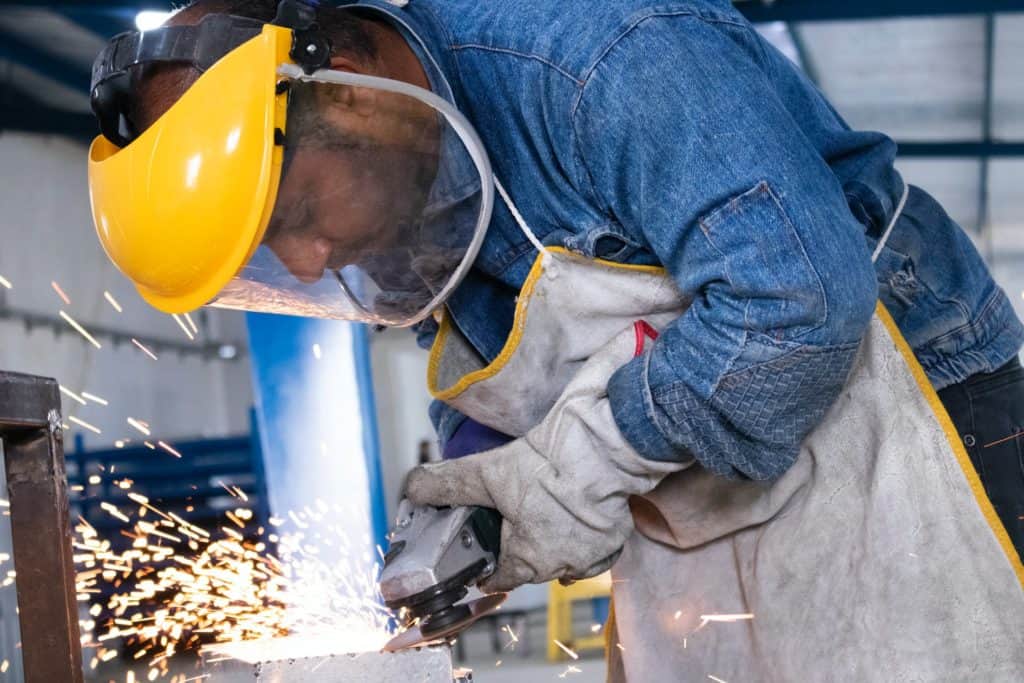 manufacturing worker cutting a piece of metal